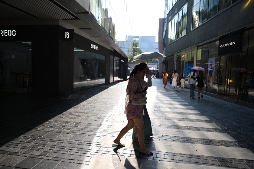 一名妇女在炎热的气温下穿过城市街道