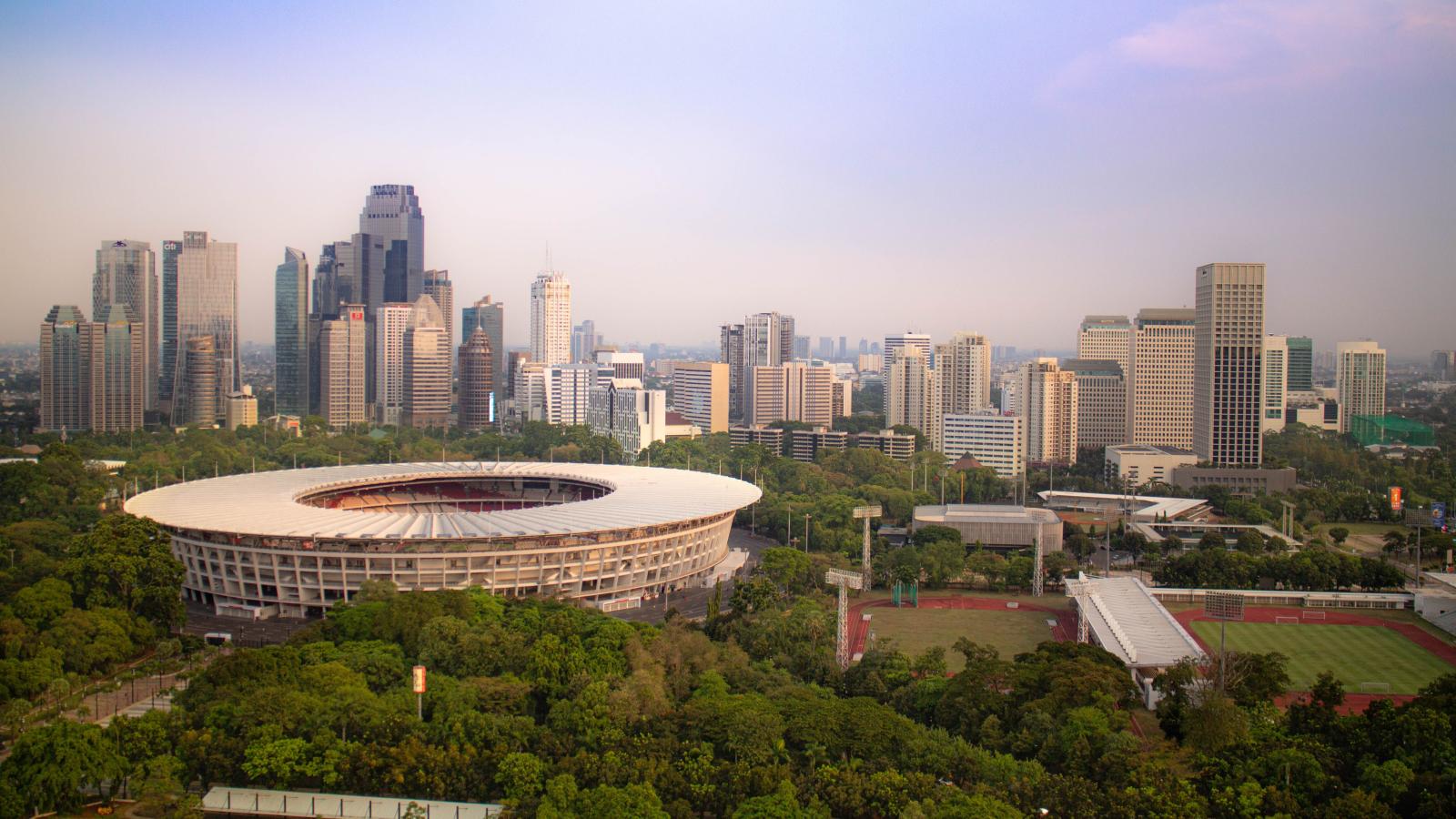 雅加达 Gelora Bung Karno 体育场的景色，周围是树木和城市天际线