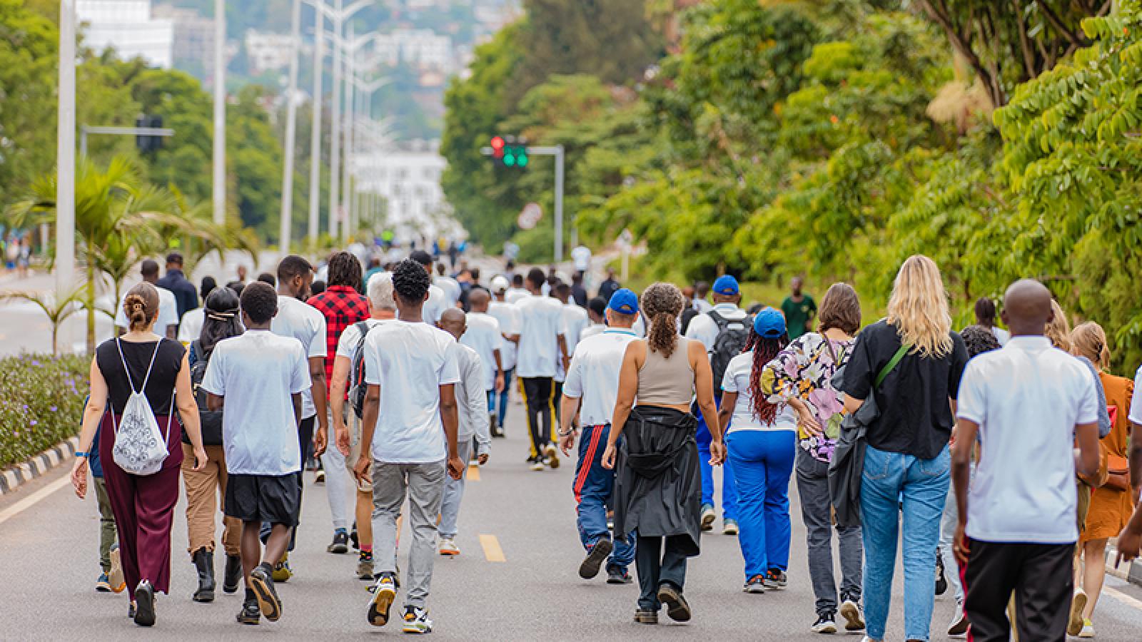一群人走在基加利绿树成荫的无车街道上