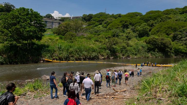 哥斯达黎加城市学院的学员们沿着维里利亚河岸步行，参观垃圾拦截塑料屏障。
